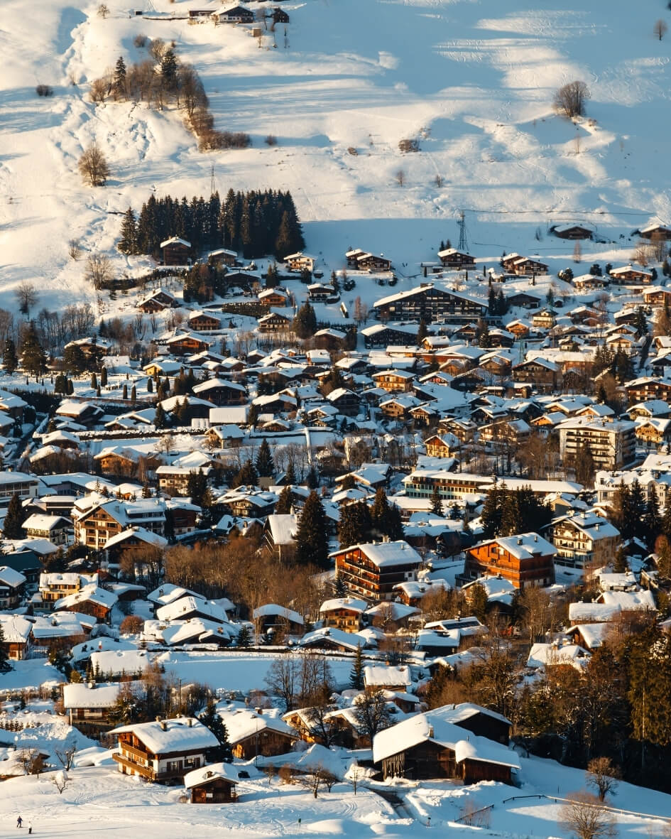Snowy ski slopes and wintery chalets nestled among evergreen trees in Megeve, France.