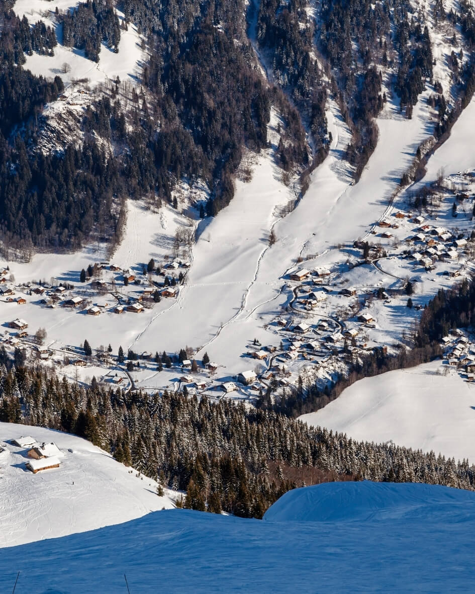 Ski slopes along the southeastern alps in Megeve, France with snow covered evergreen trees.