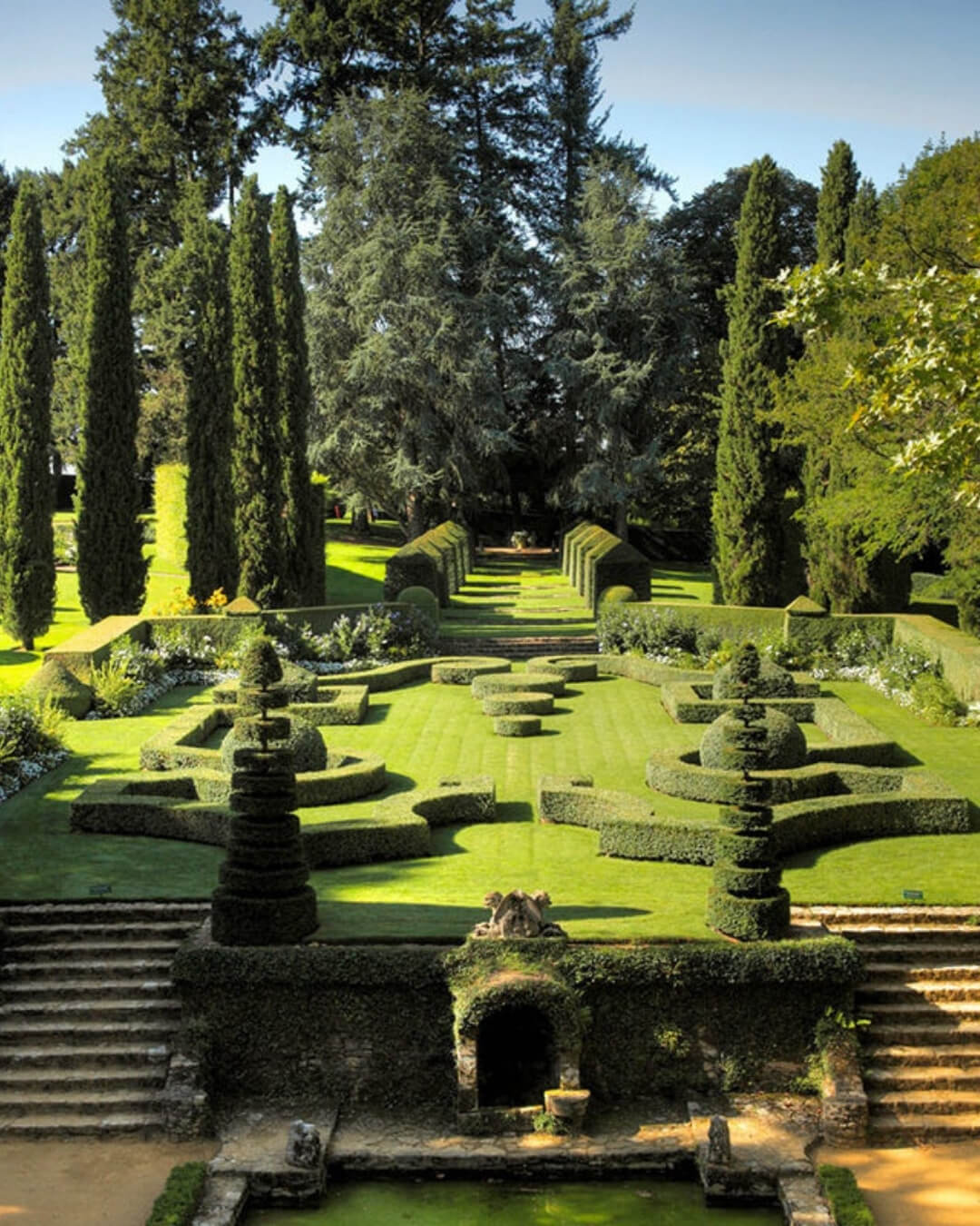 The Gardens of Eyrignac Manor with topiary style hedges, cypress trees, and historic stone steps.