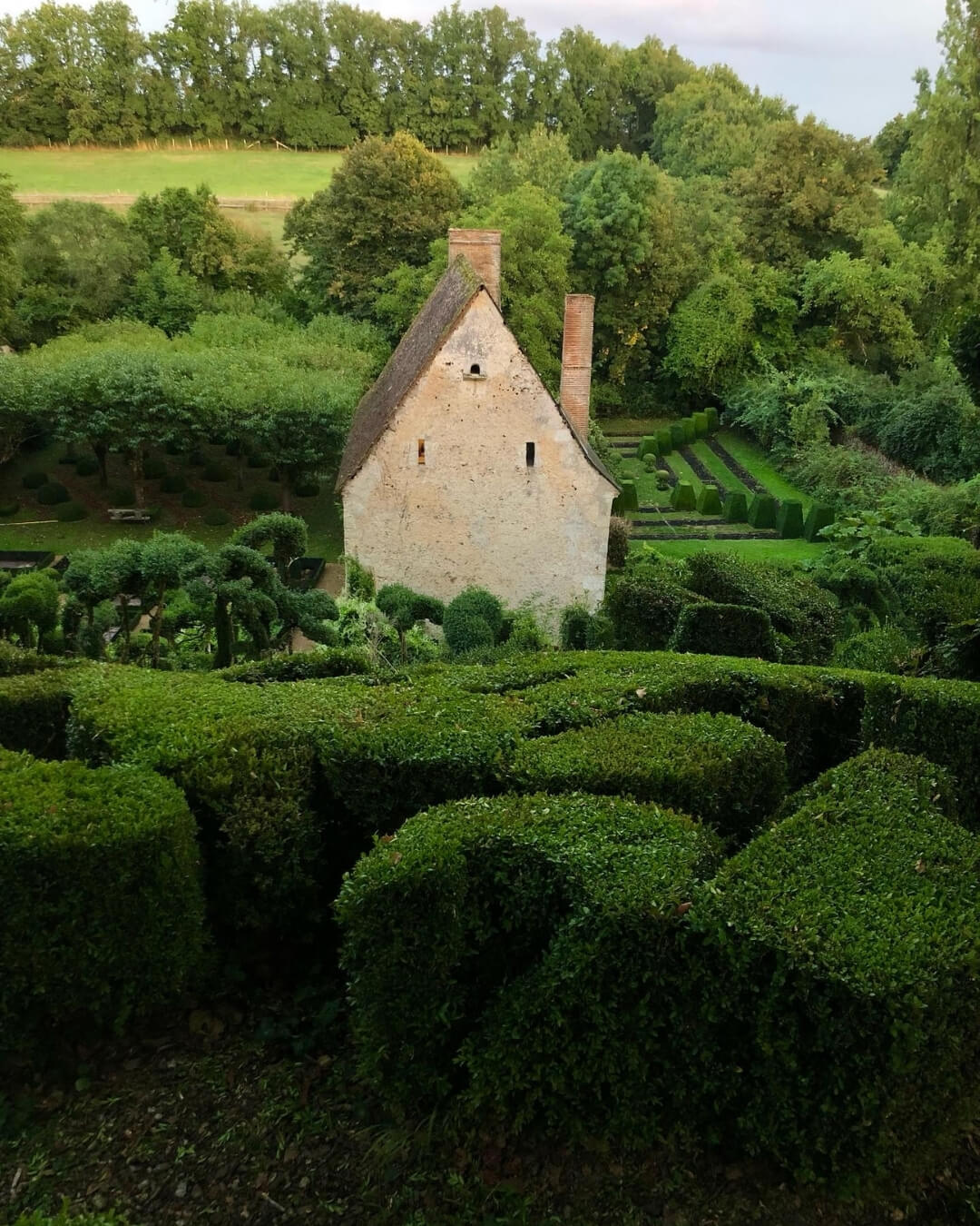 Lush Prieure-Vauboin gardens on a hilly manicured landscape in Beaumont-sur-Dême, France.