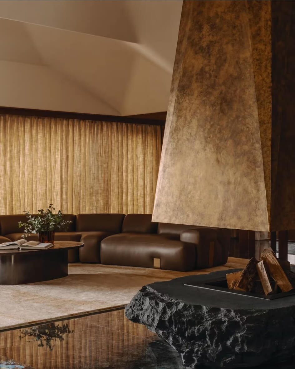 Interior of the Rosewood Courchevel ski chalet salon with a modern exposed fireplace and buttery leather sofas.