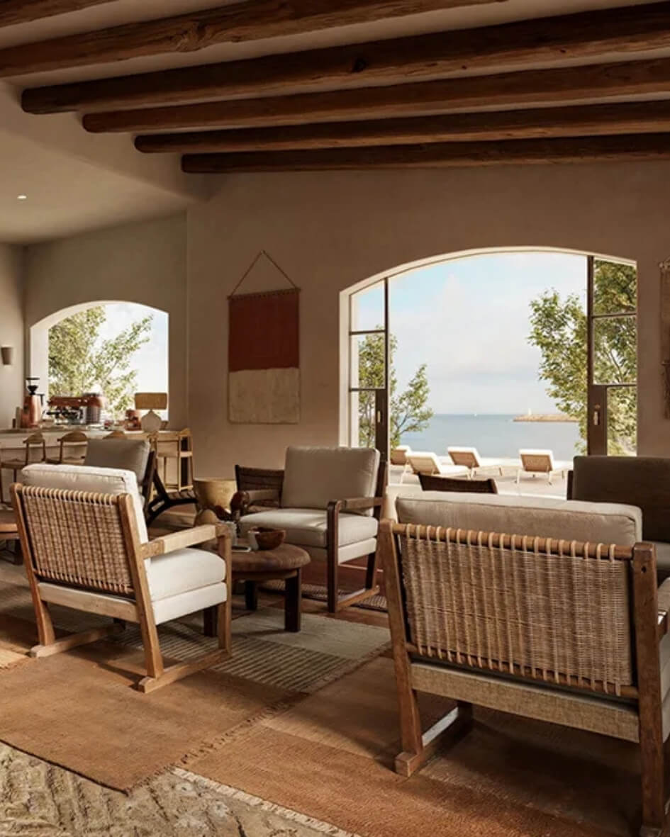 Zannier Hotel salon interior with wicker chairs and large open windows facing the ocean.