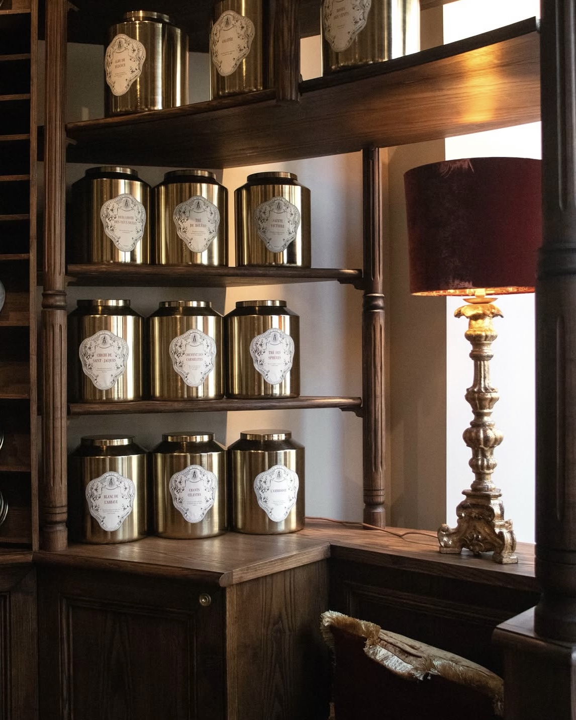 Conservatoire des Hémisphères tea boutique in Paris, France, with tea displayed in gold canisters under soft lighting.