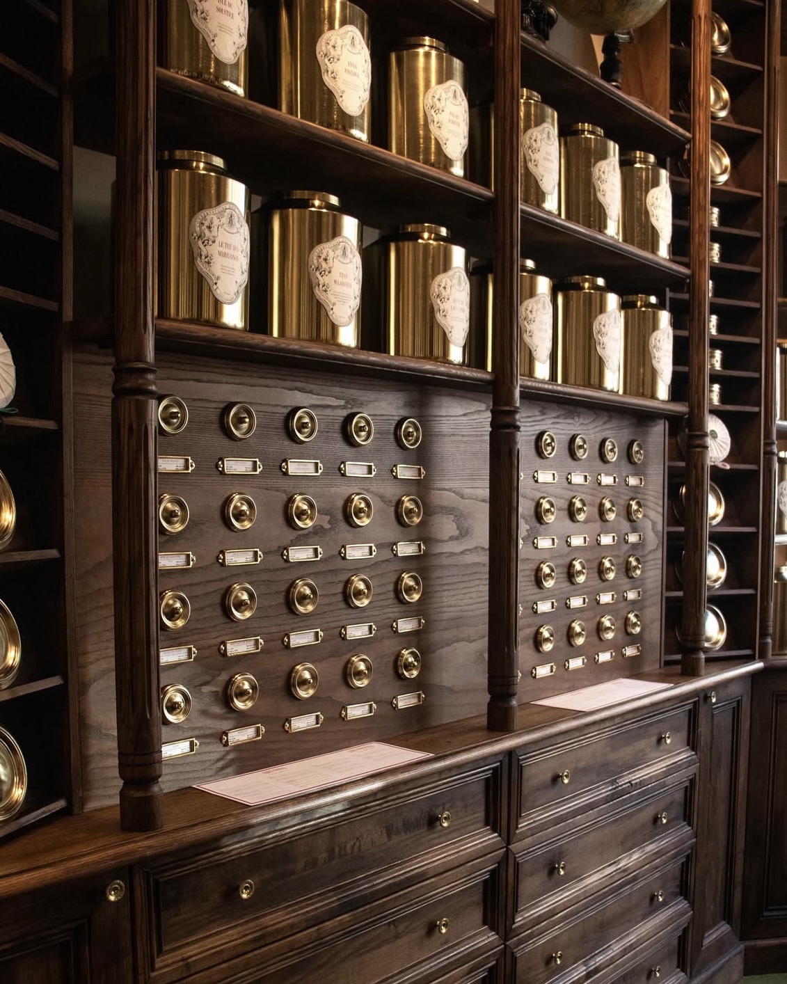 Apothecary style display with gold canisters of tea at Conservatoire des Hémisphères in Paris.