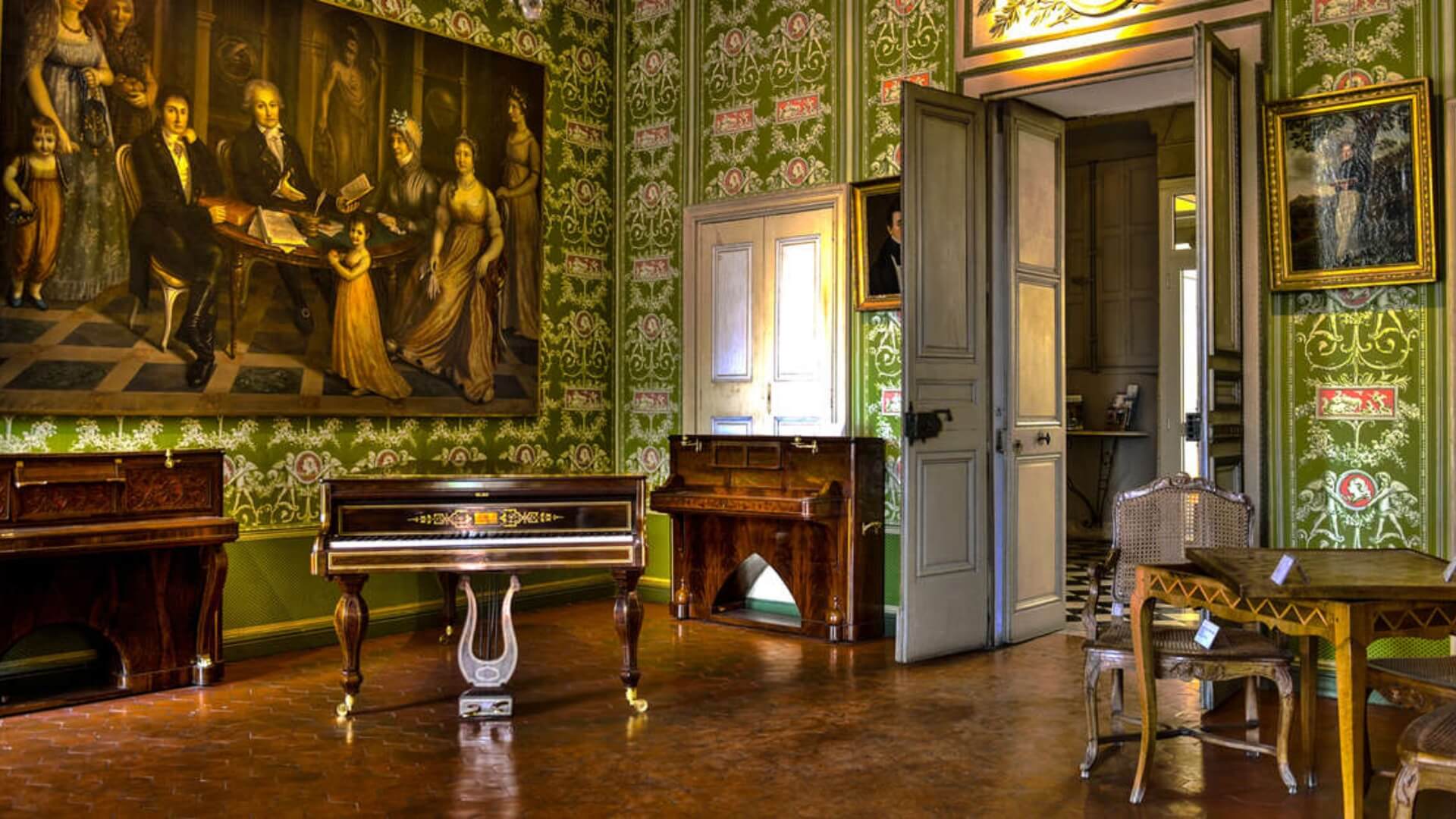 Interior of the Provence Art and History Museum in Grasse, featuring ornate green wallpaper and antique French furniture.