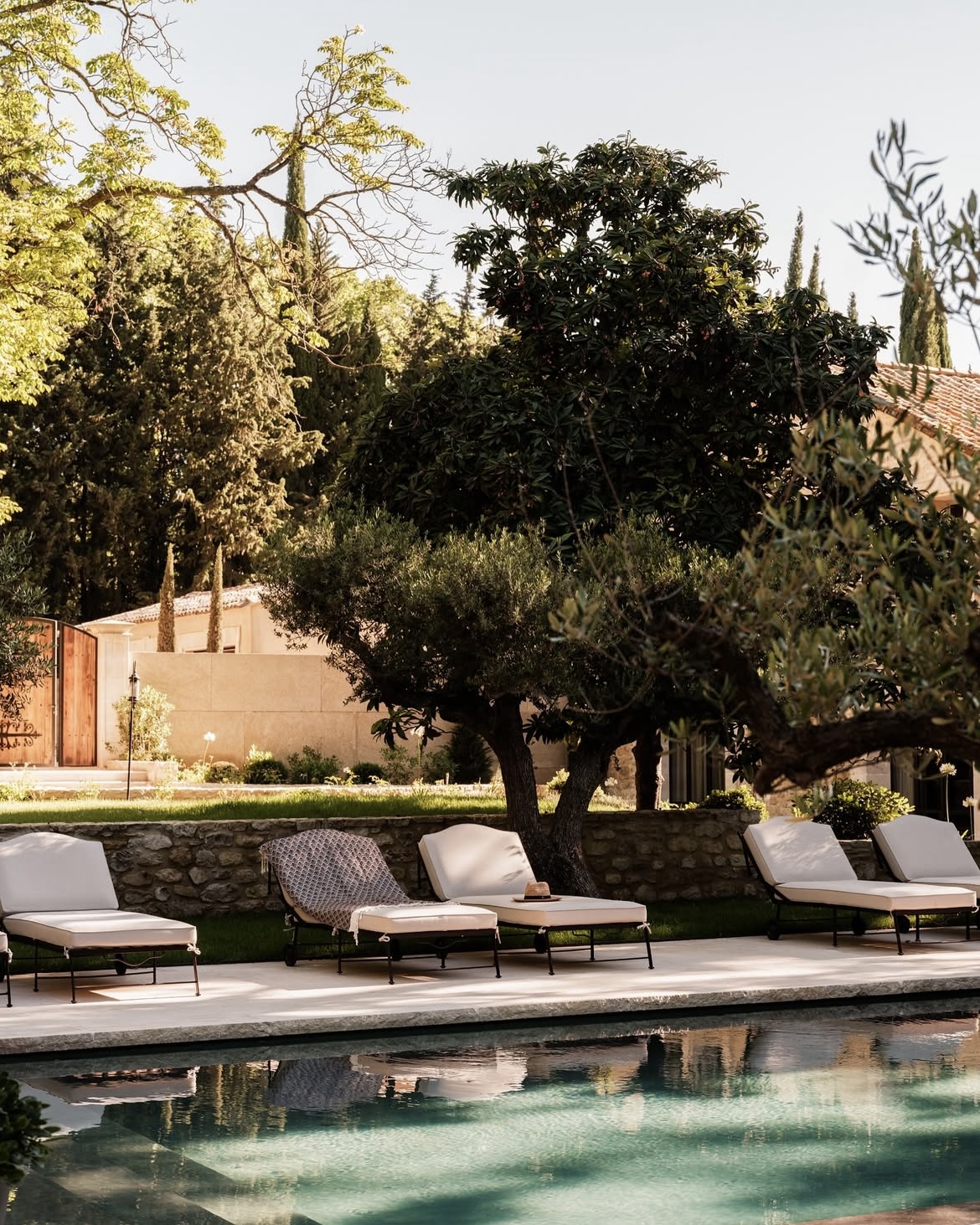 Villa swimming pool and chaise lounges beside a lush garden in Provence.