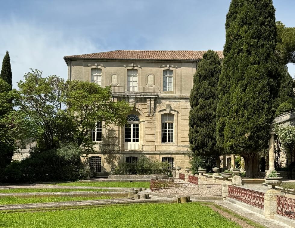 Historic estate exterior and garden in Provence, France with decorative iron fences.