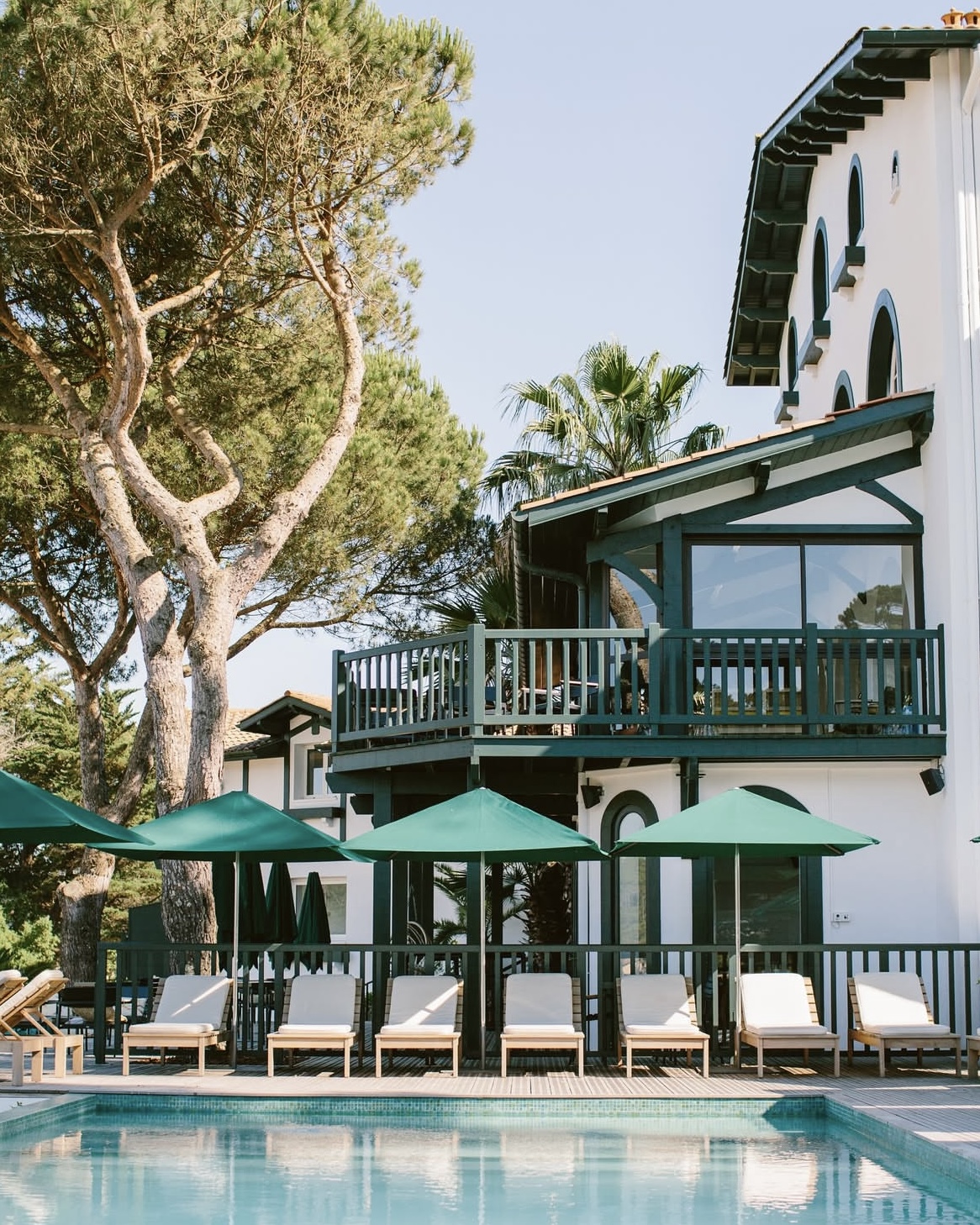 Outdoor swimming pool at Domaine de Fontenille hotel in Provence with shaded chaise lounges and teal accents.