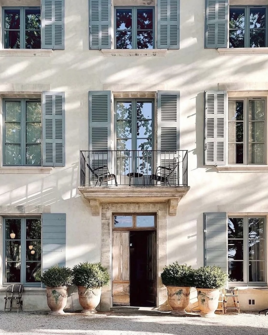 Domaine de Fontenille exterior with shuttered lined French windows, potted plants, and an intimate terrace.