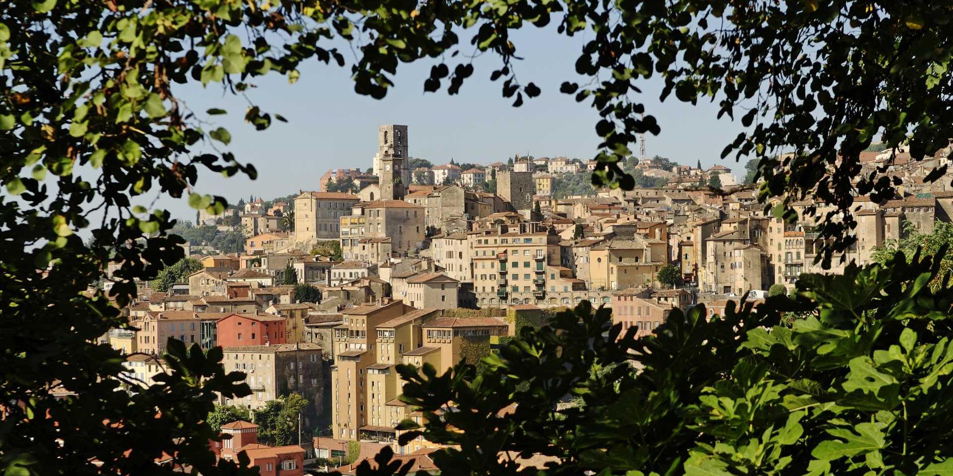 View of the cityscape between lush green foliage in Grasse, France.