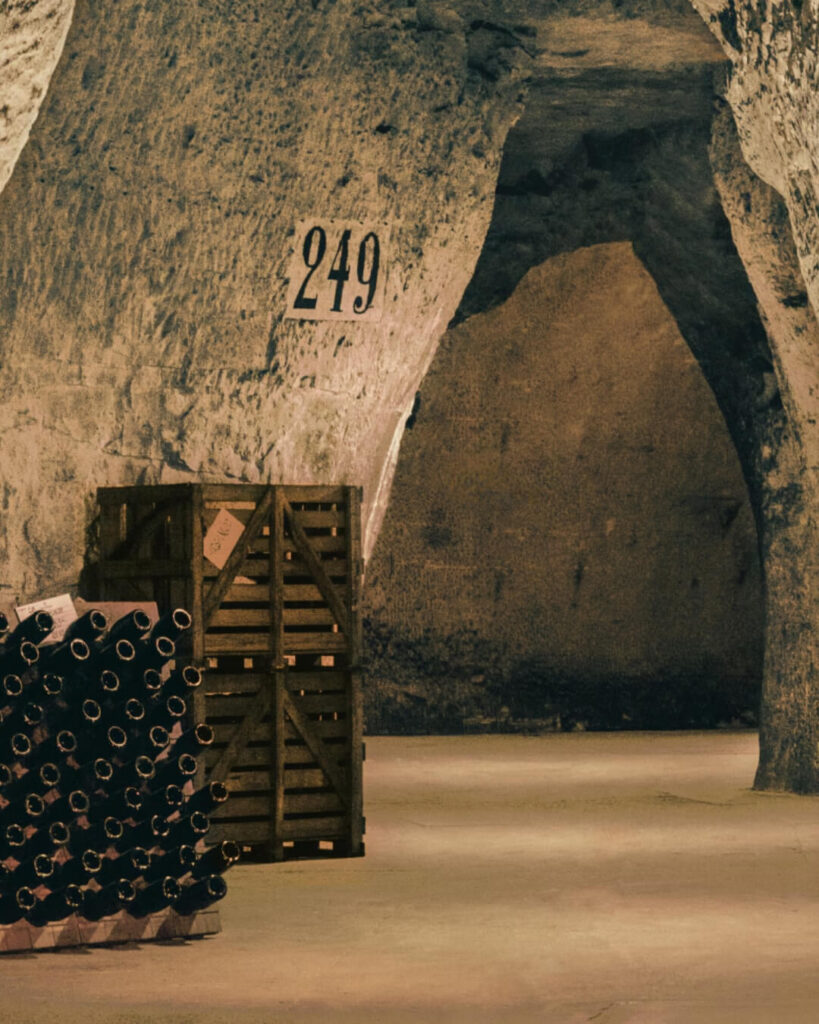 Historic stone champagne cellar in France, with wooden crates along the wall.