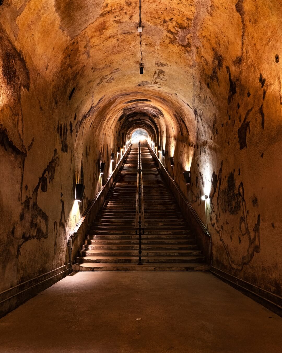 Stairs from a historic wine cellar with soft, dim lighting along the stairs leading up to the main floor in Champagne, France.
