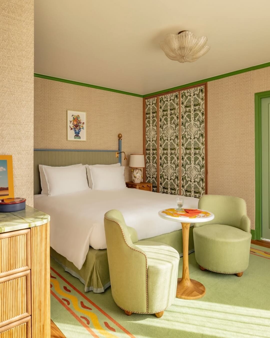 La Fantasie boutique hotel room in Paris with mint green accents, modern furniture, and intricate wallpaper.