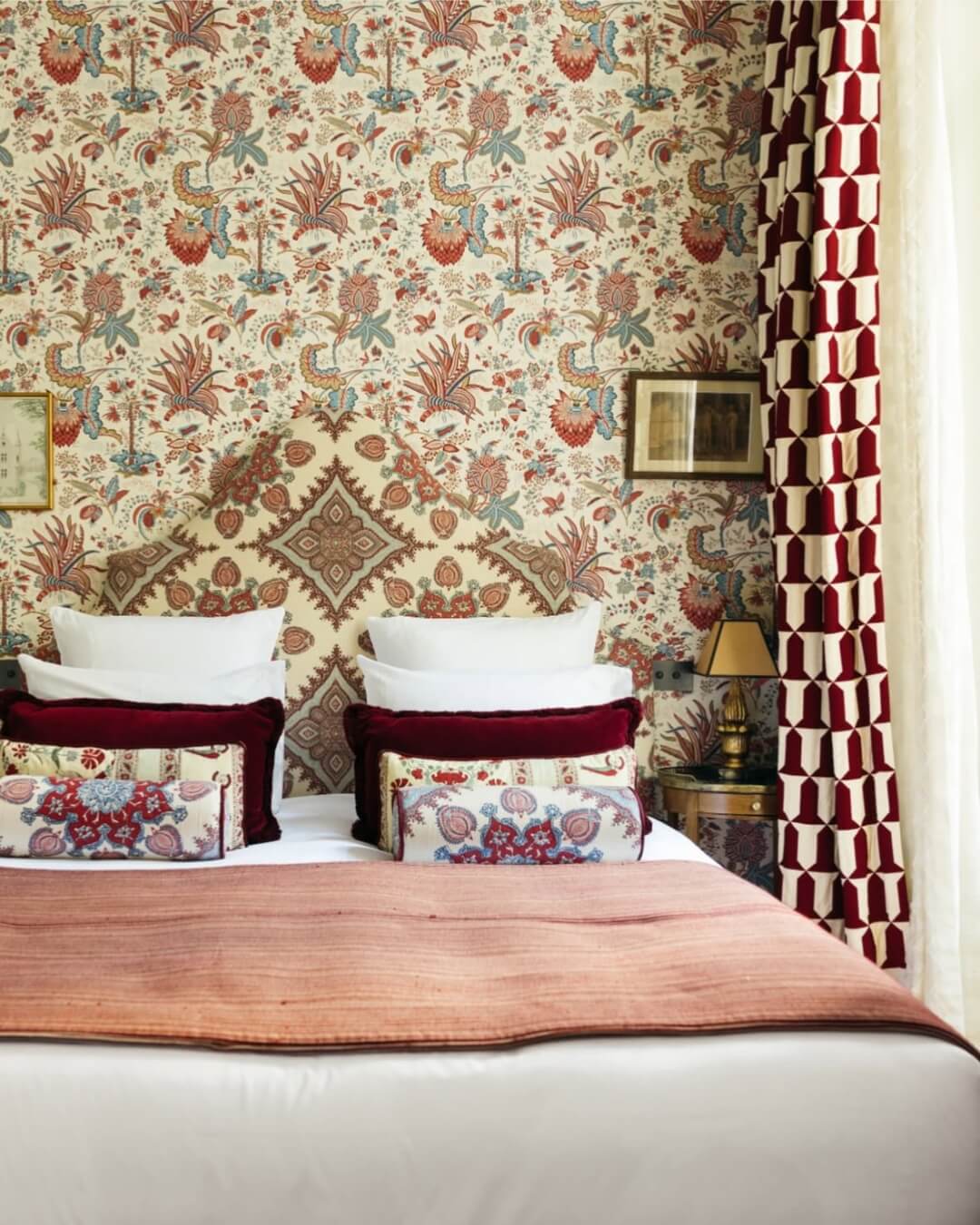 Relais Christine luxury hotel room interior with ornately patterned wallpaper and complimentary red and white bed linens in Paris, France.