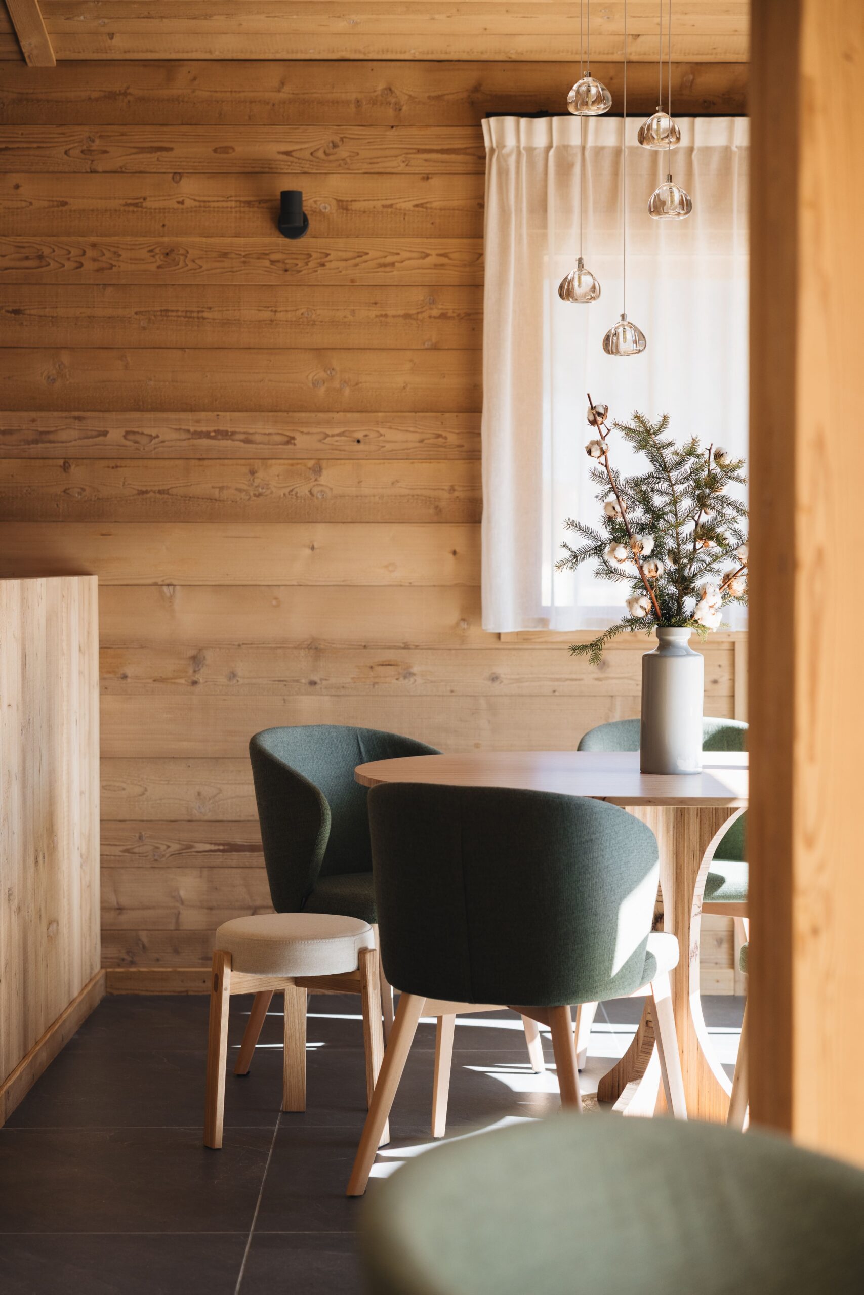 Chalet style dining room at a French restaurant with green accents and freshly cut decorative pine.