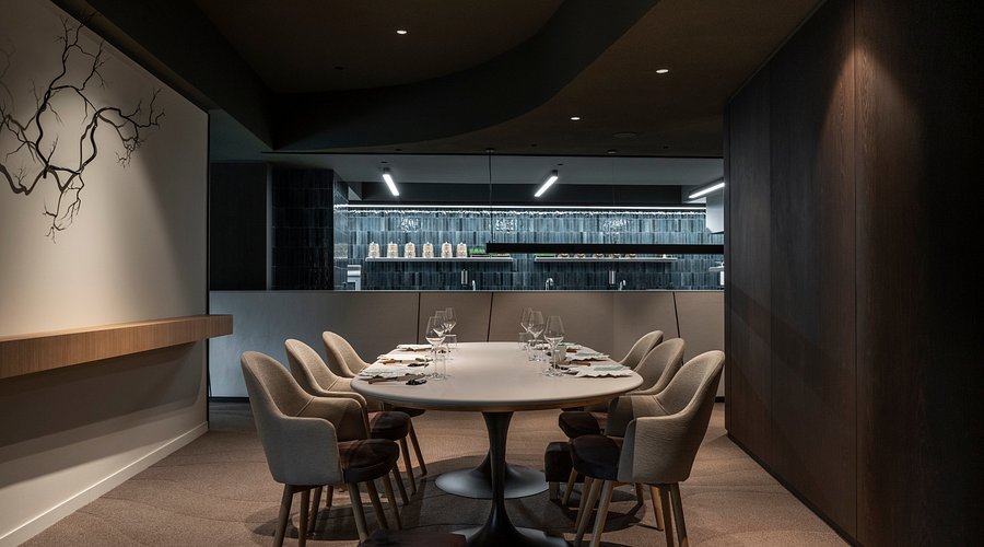 Michelin Star Arbane Reims restaurant dining interior with minimalist design and a kitchen view.