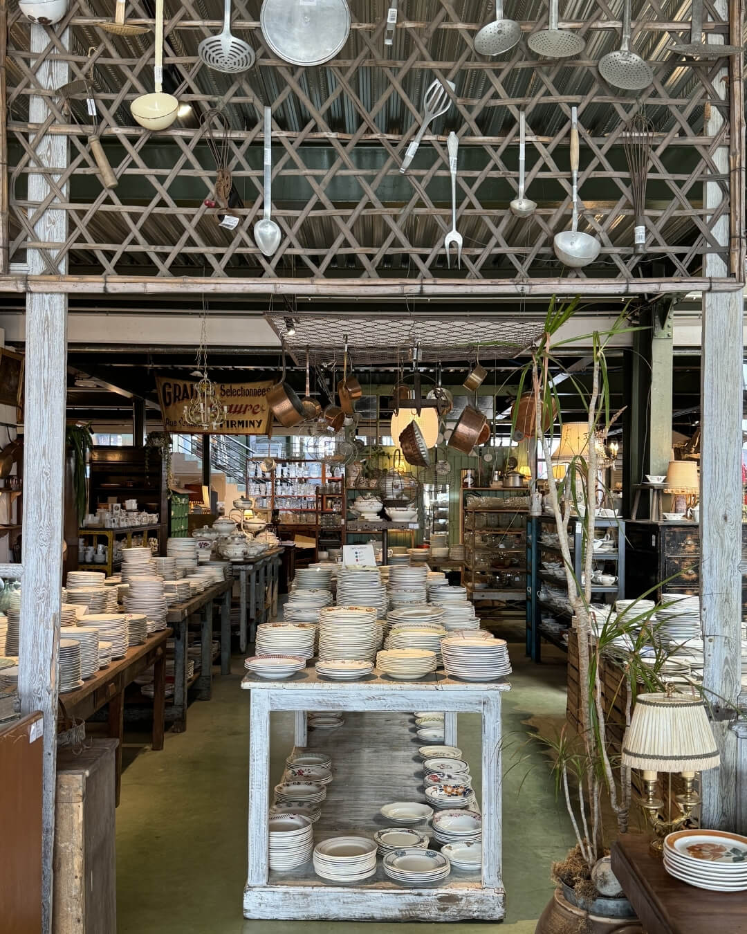 French porcelain dishes displayed on a rustic table in a Parisian antique market.