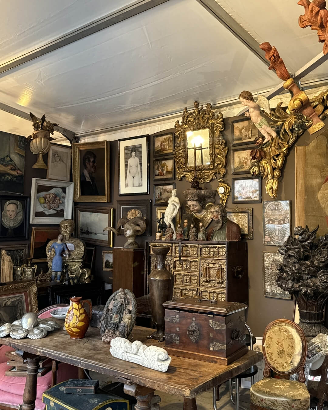 French anti market with framed paintings, gilded mirrors, and statues.