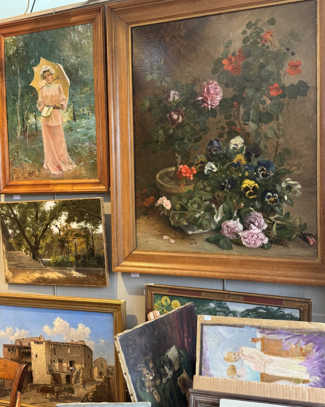 Framed oil paintings on display in a French market.