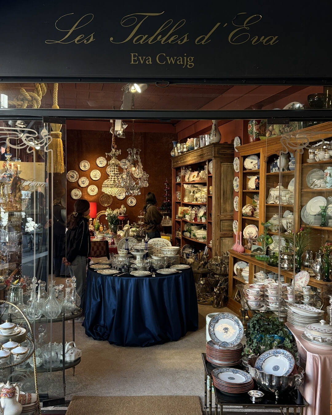French porcelain plates, crystal decanters, and chandeliers on display at Les Tables d'Eva in Paris, France.