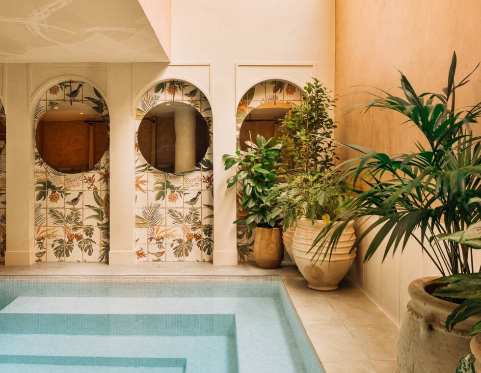 Indoor swimming pool at Bloom Spa in Paris, with painted tiles and potted plants along the walls.