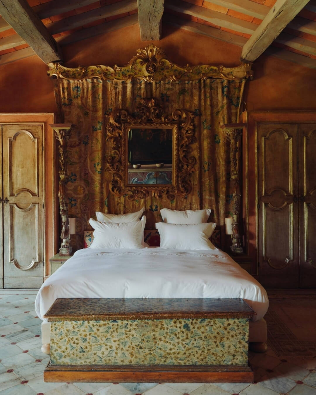 Boutique hotel room in La Cavalerie, France with antique French furniture, ornate wood detailing, and exposed beams.