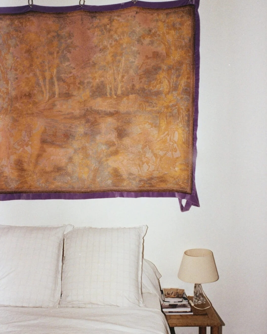 Minimalist bedroom at Pavillon Southway in Marseille with simple decor and a colorful tapestry hanging above the bed.