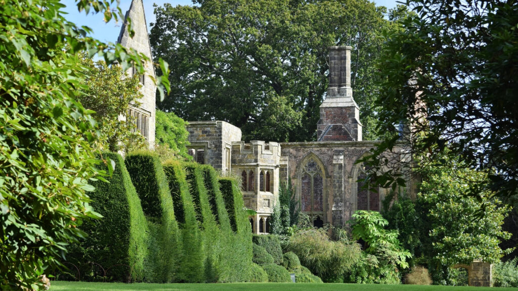English garden in Sussex with lush manicured hedges and historic stone church.