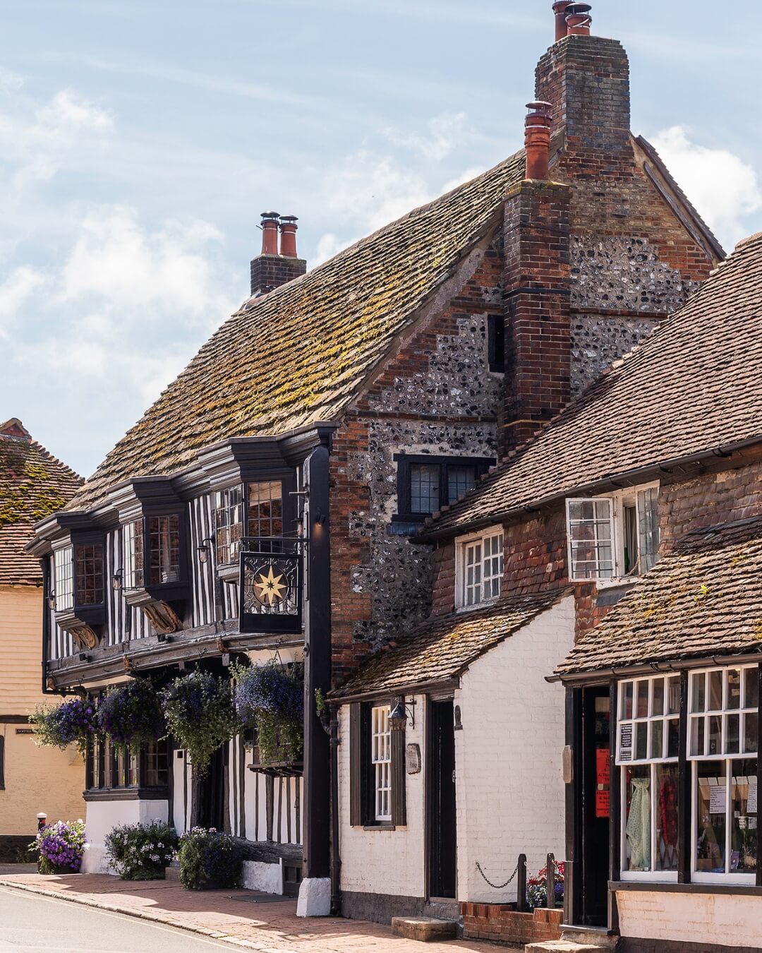 The Star boutique hotel exterior with cottage style brick, featuring hanging flowers and potted plants in Sussex, England.