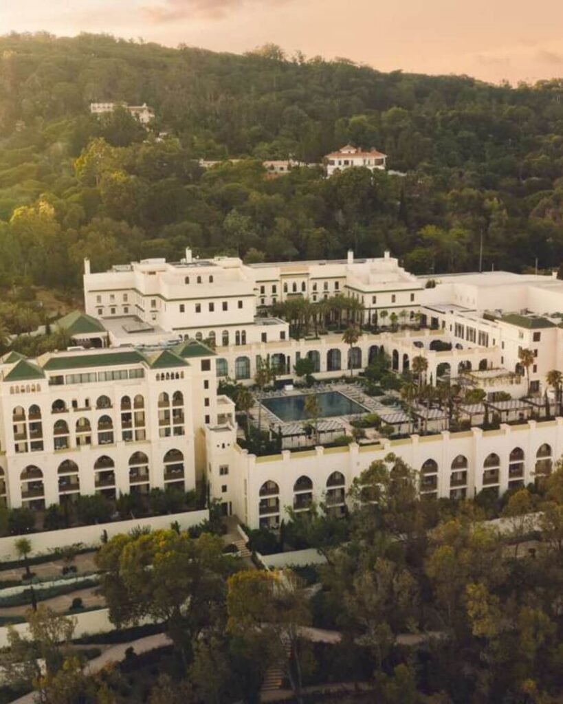 Fairmont Tazi Palace in Tangier, Morocco featuring a tiled swimming pool, bright open windows, and lush surrounding greenery.
