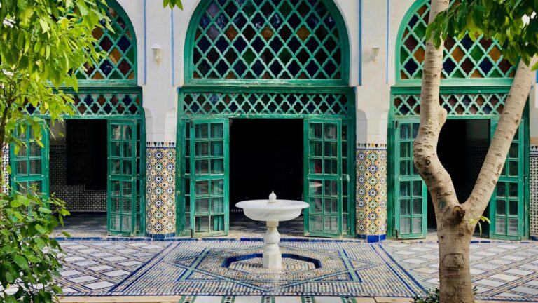 Moroccan riad featuring tiled floors, arched windows, and a stone fountain.