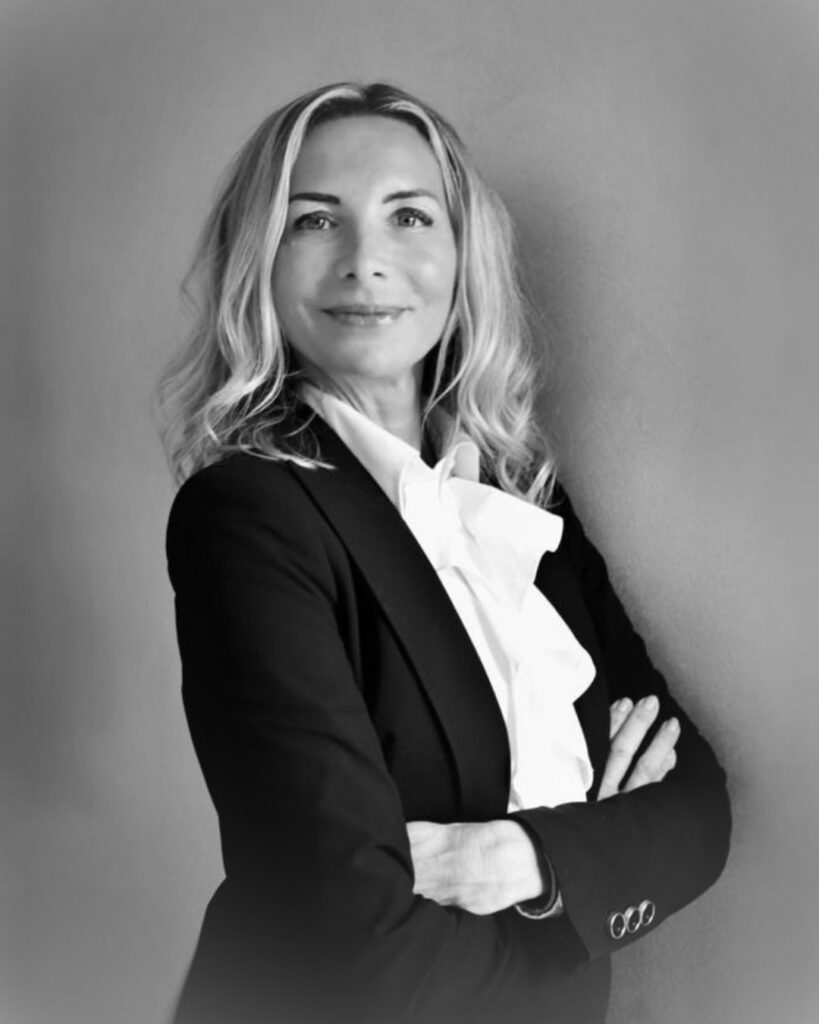 Portrait of Monica Ginnaio leaning against a wall and smiling.