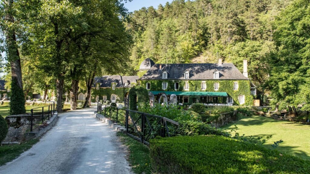 Manoir d’Hautegente in Dordogne, France with a lush green garden and climbing ivy along the building exterior.