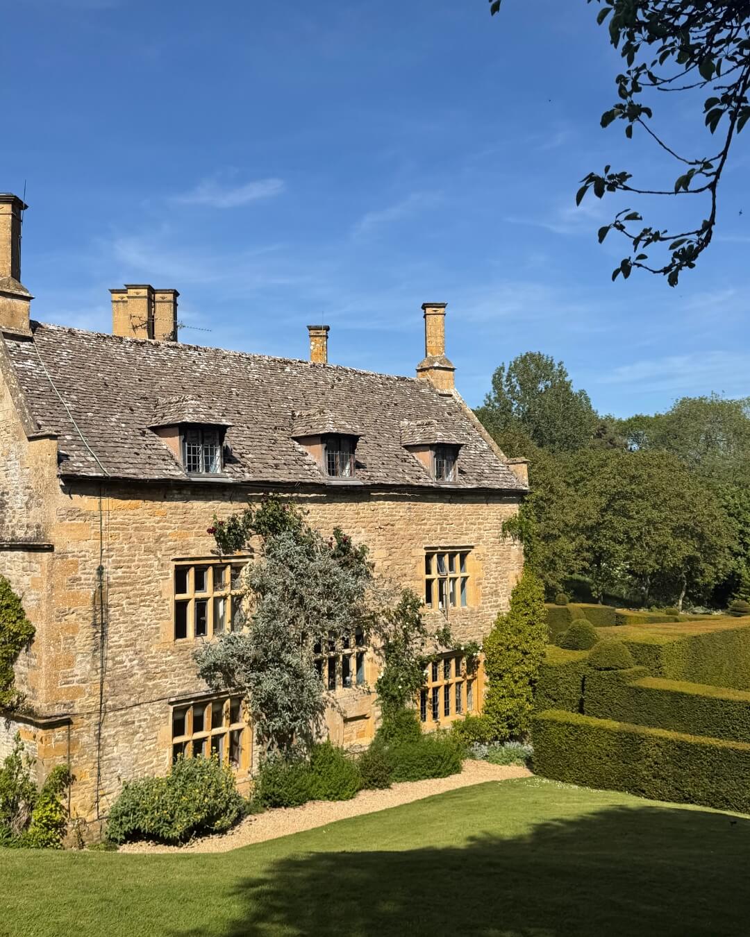 Historic Upton Wold estate and garden with lush green gardens and manicured hedges in Blockley, England.