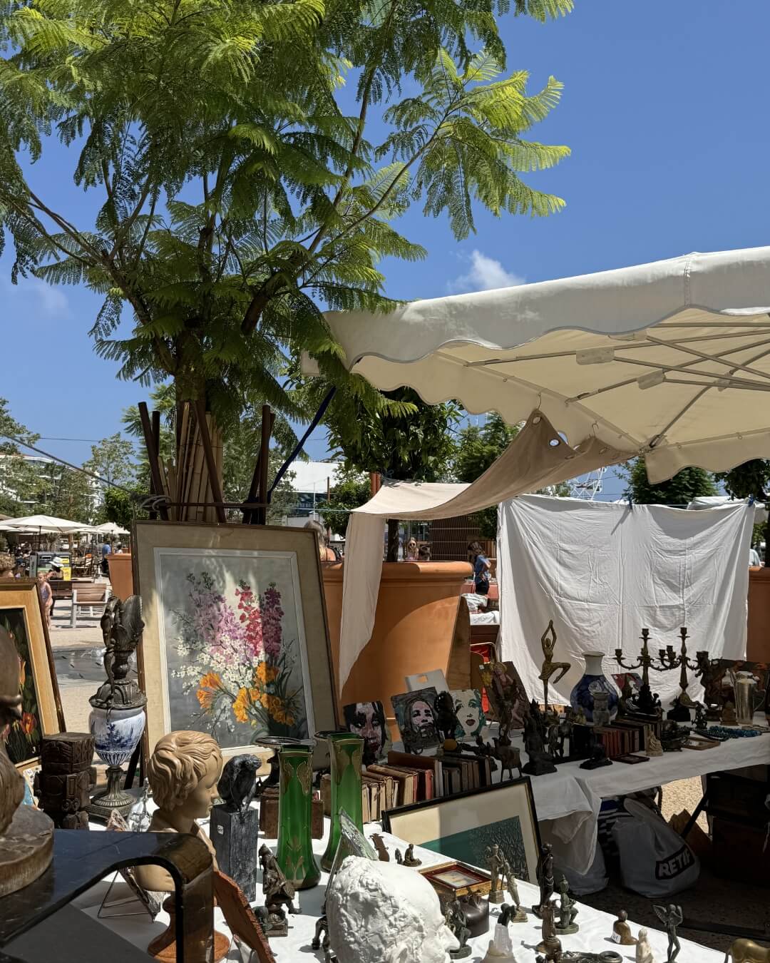 Antique market table along the French Riviera featuring books, art, and sculptures.
