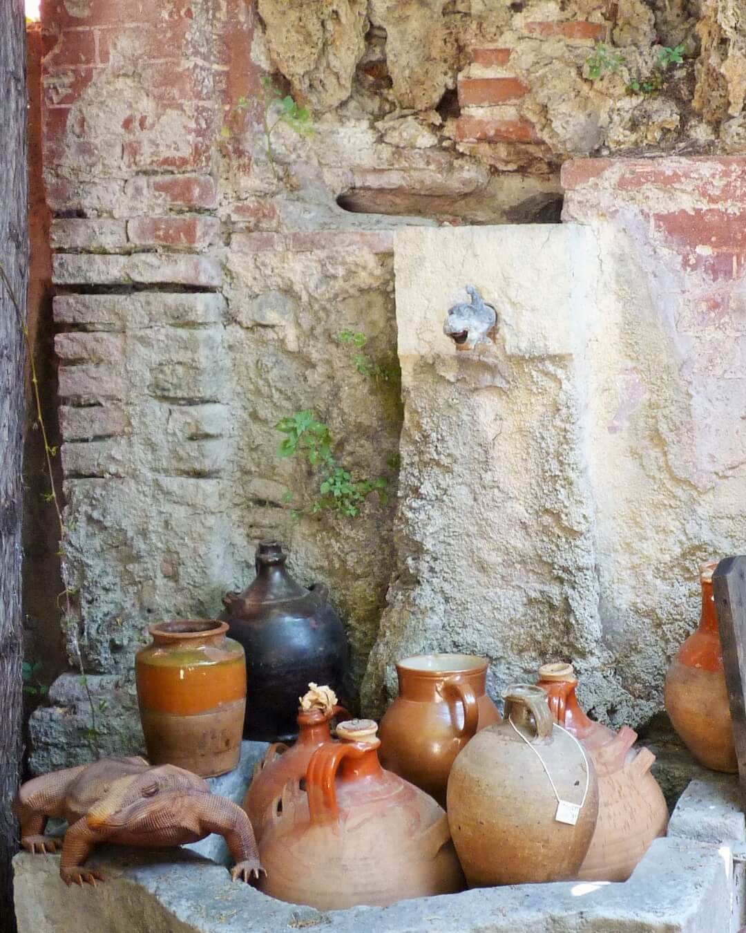Ceramic pots and vases displayed in a historic fountain at an antique fair on the French Riviera.