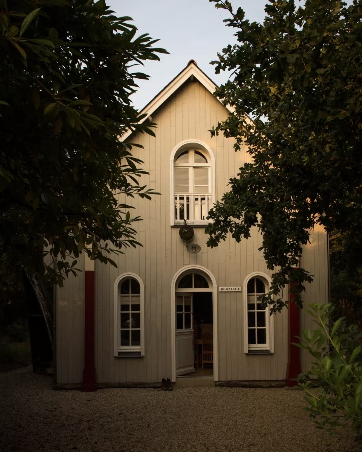 Maisons de Bricourt, A-frame exterior at sunset, surrounded by lush green trees.
