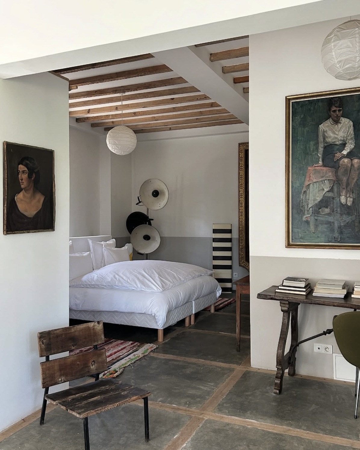 Villa Magnan hotel room interior featuring stone floors, exposed beams, and vintage art.