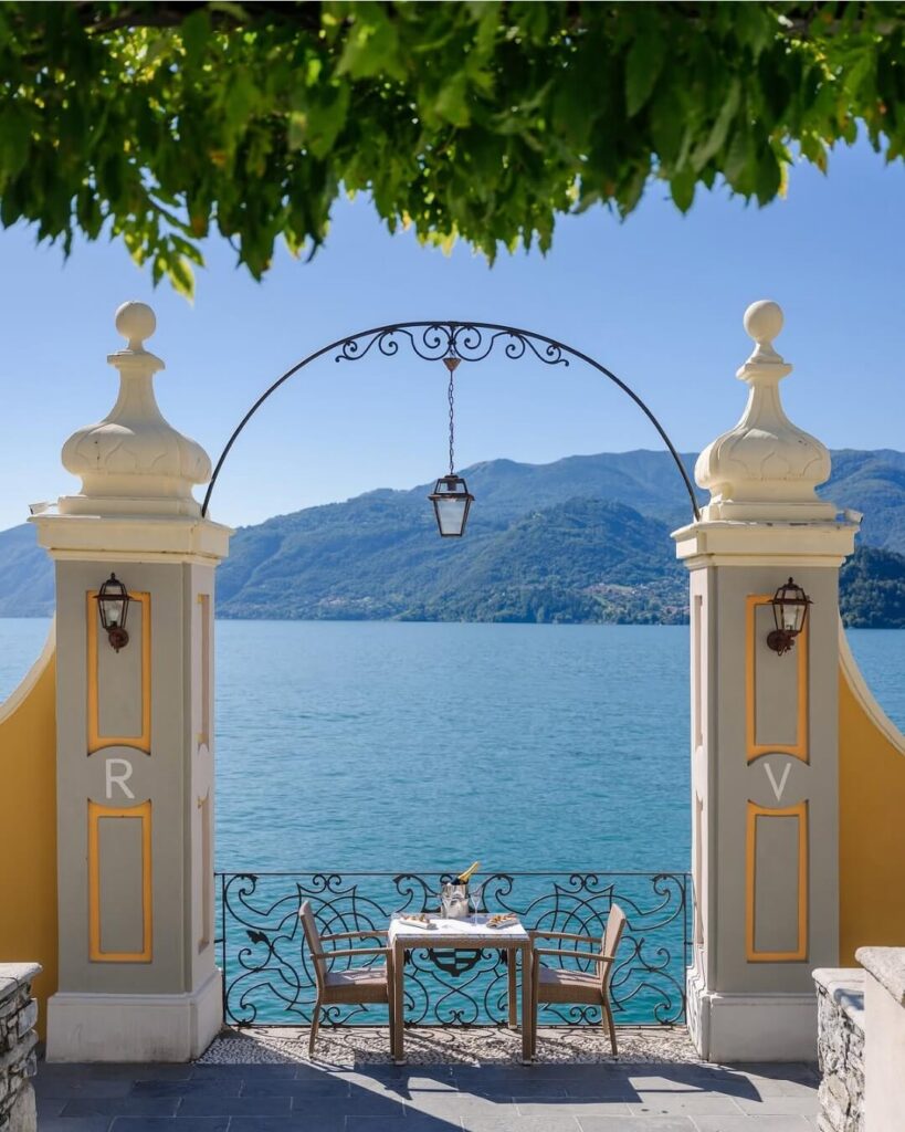 Intimate garden dining table over looking Lake Como, framed by an ornate iron arch.