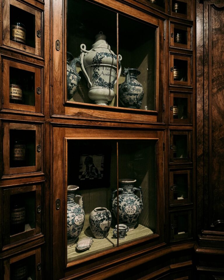Antique apothecary cabinet with vintage ceramic vases on display in Paris, France.