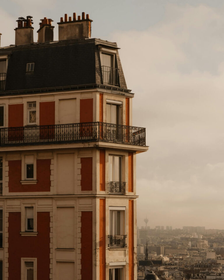 Tall red Parisian style apartment building in France with views of the city skyline.