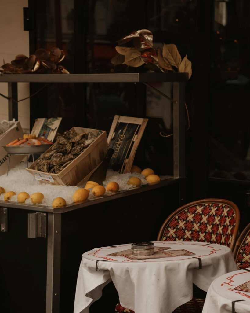 Parisian bistro chairs and tables beside a fresh seafood display in France.