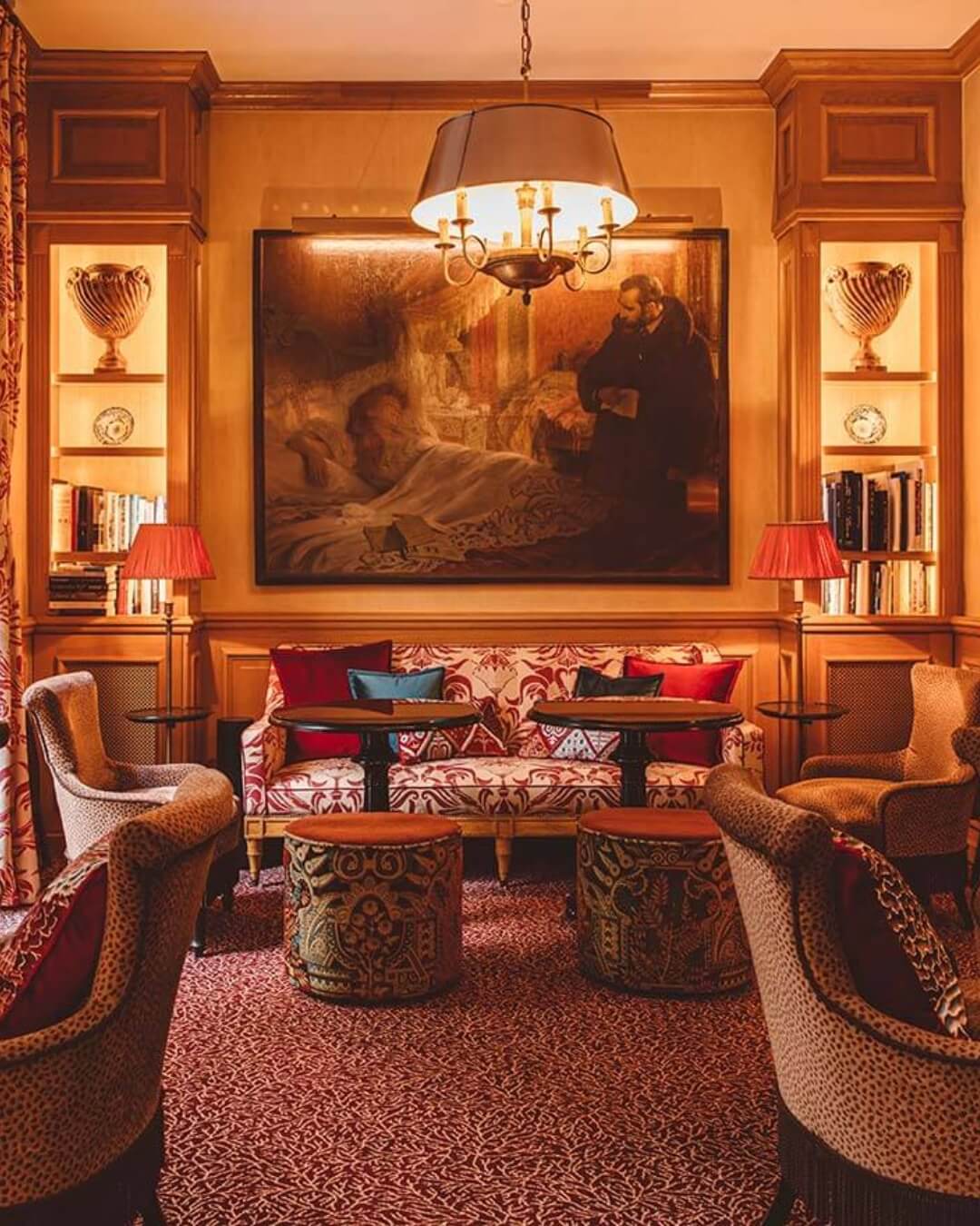 Luxury hotel salon interior in Paris, France with ornate red and white furniture, framed art, and soft lighting.