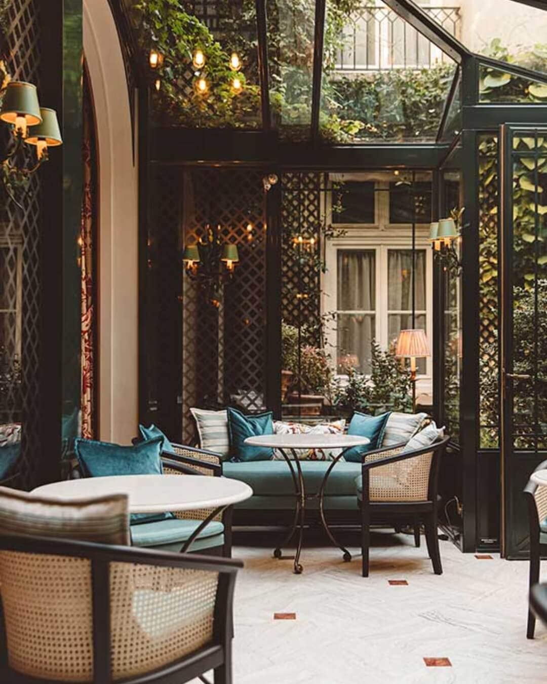Sunroom dining area with plush love seats and wicker chairs at a bed and breakfast in Paris, France.