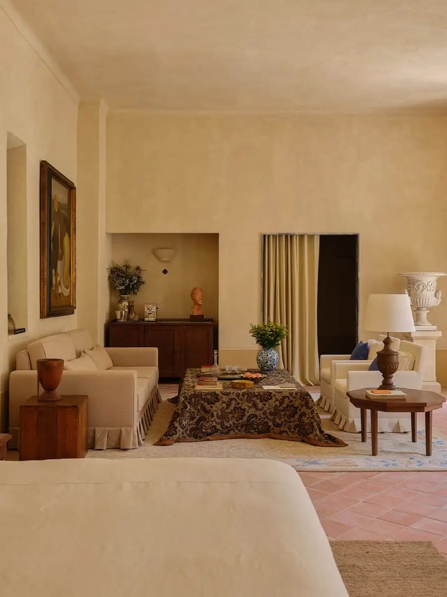 Luxury Le Chapitre suite interior at Hôtel du Couvent in Nice, France, featuring stone tiled floors and vintage furniture bathed in soft natural light.