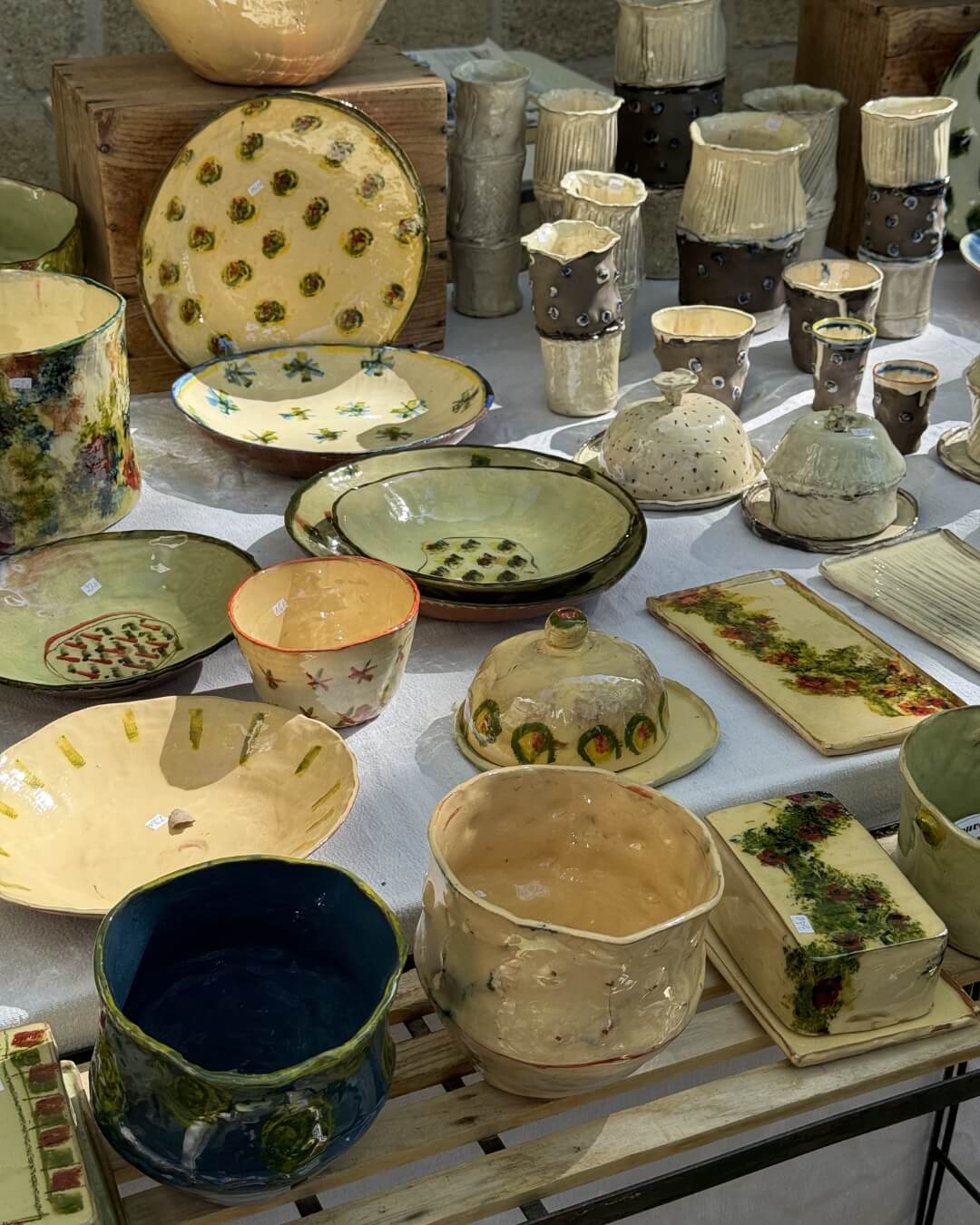 Ceramic pots, bowls, and kitchen ware displayed on a table in Provence.