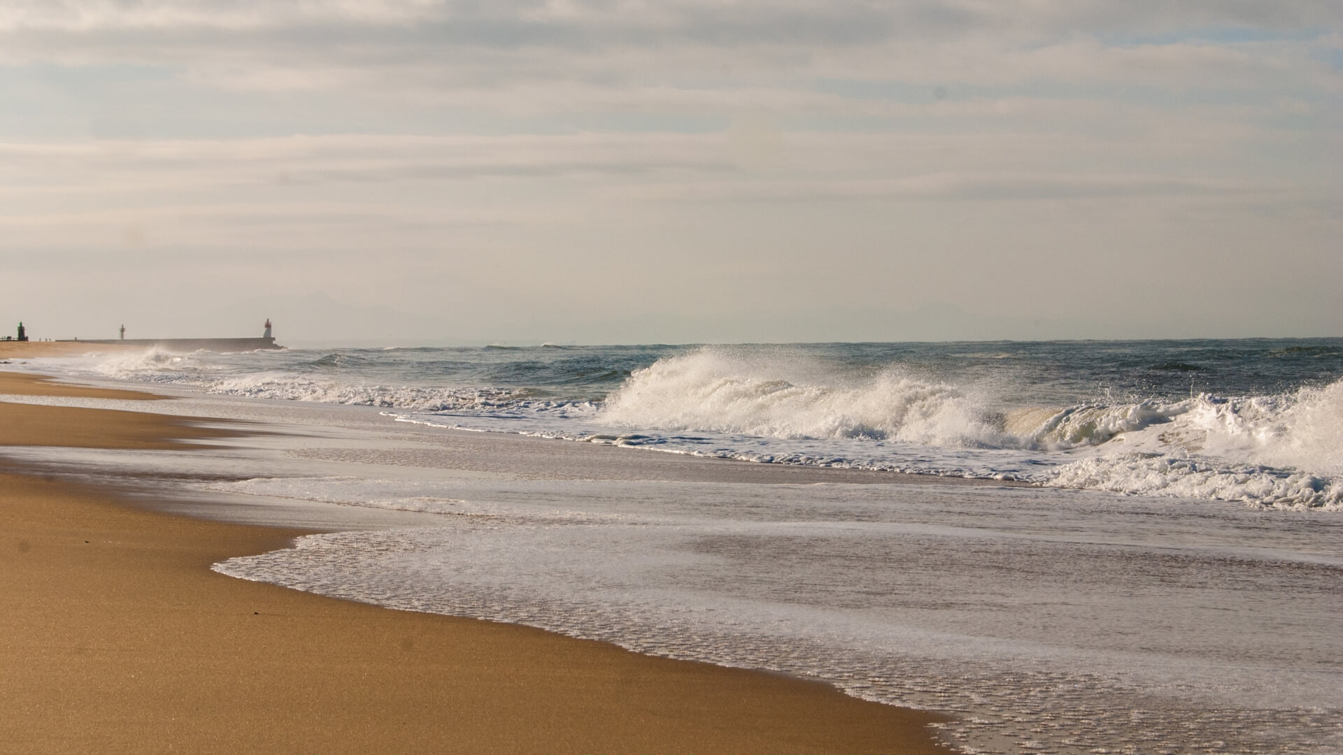 Sandy shoreline with crashing waves in Hossegor, France.