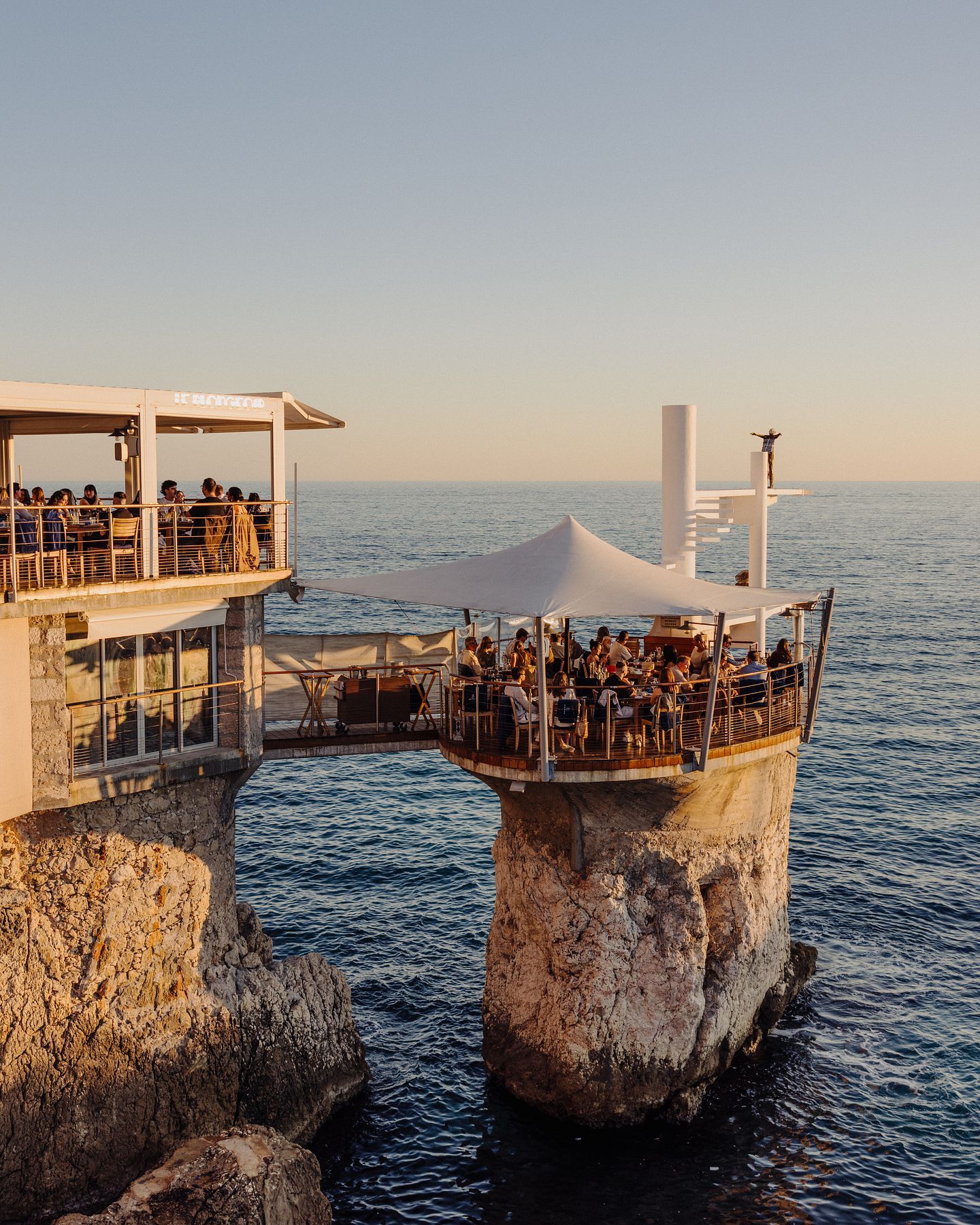 Le Plongeoir cliffside restaurant terrace overlooking the Mediterranean Sea along the French Riviera.