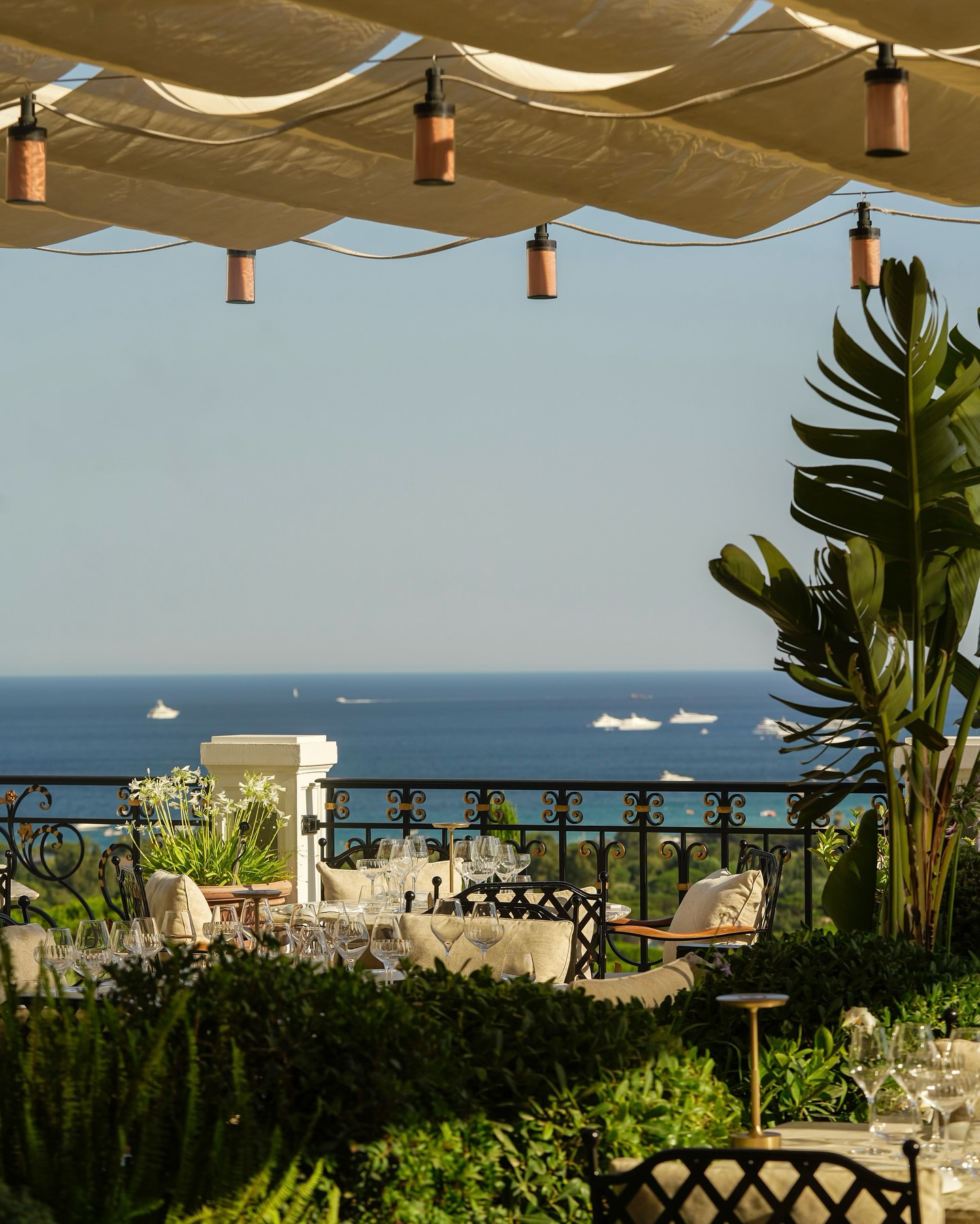 La Messardiere hotel terrace with intimate dining tables over looking the Mediterranean Sea dotted with white yachts.
