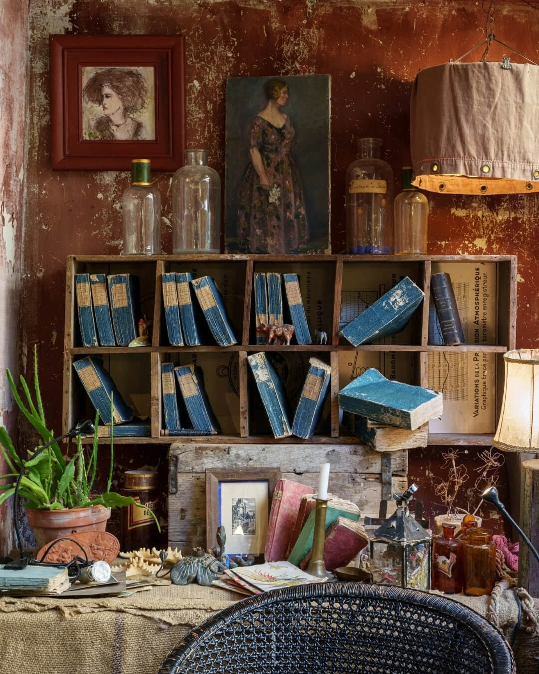 Desk with vintage books and art arranged against a rustic ocher colored wall.